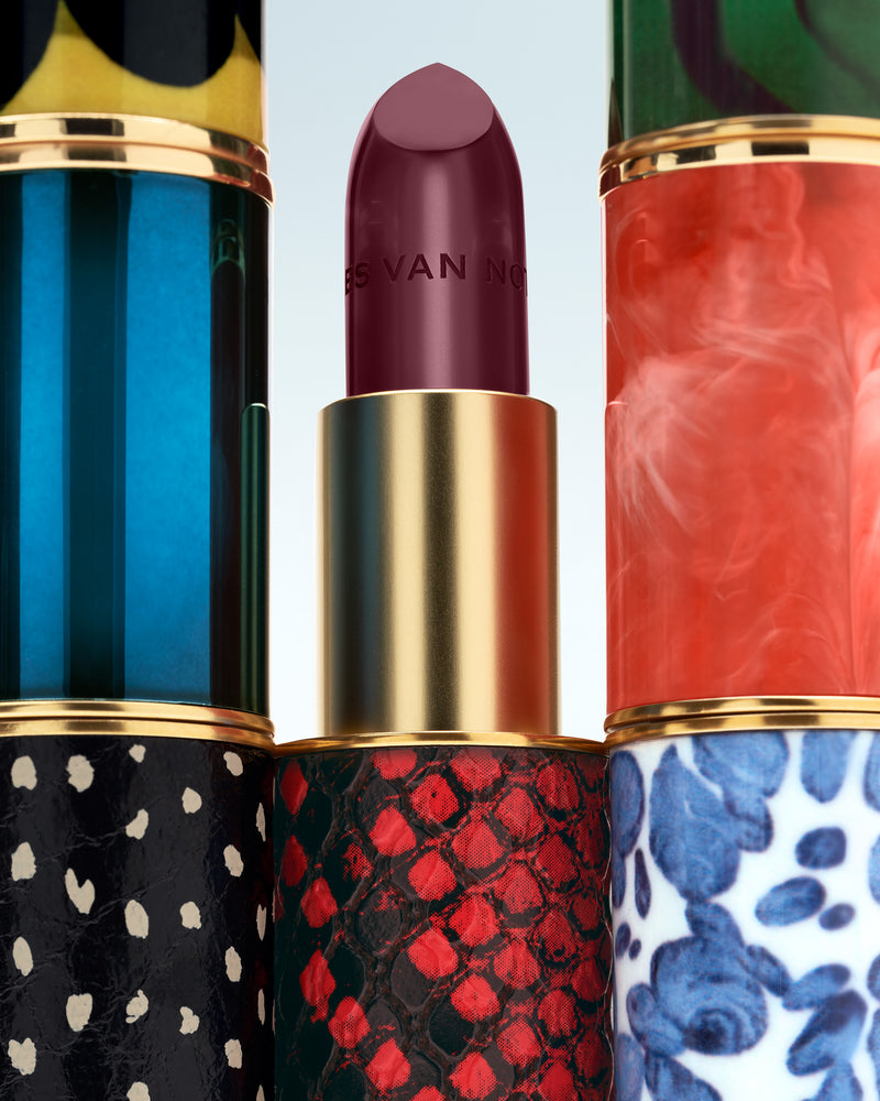 Three colorful lipsticks with patterned cases on a light blue background