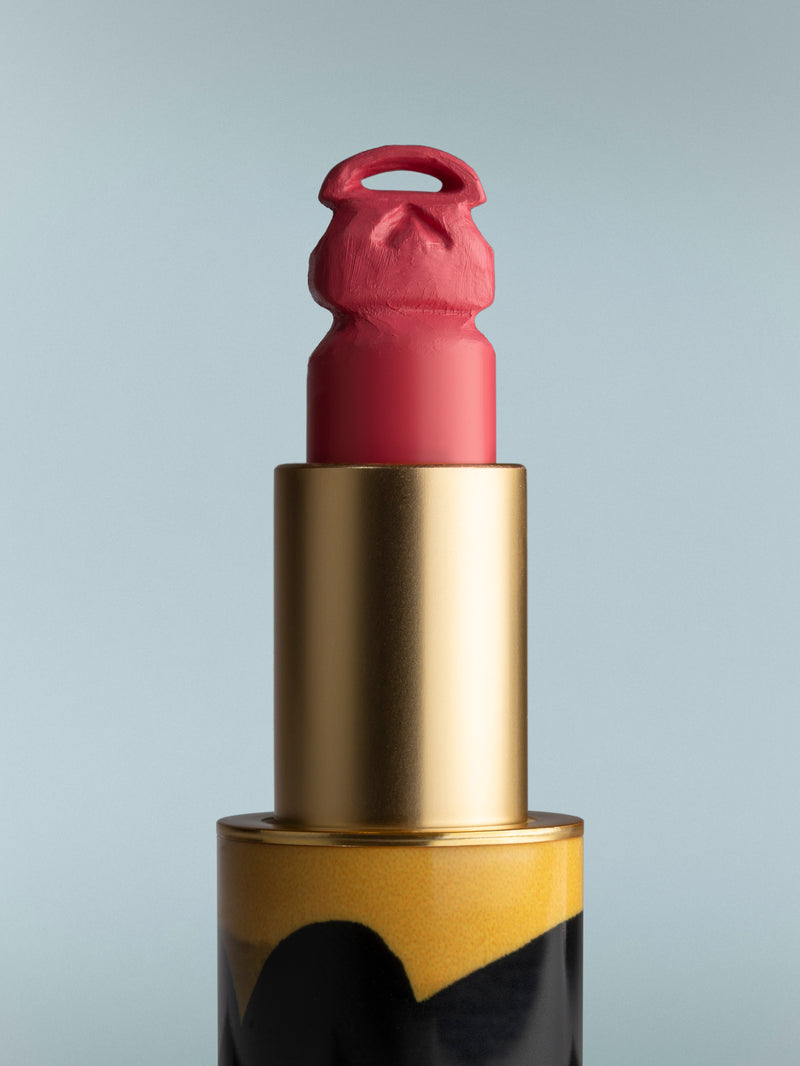 Lipstick with gold casing on a gray background