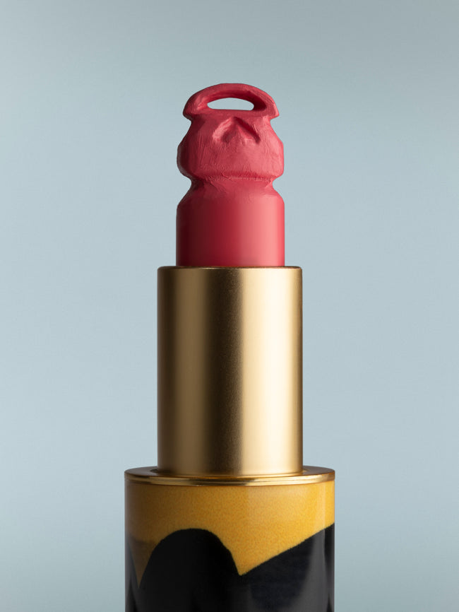 Lipstick with gold casing on a gray background