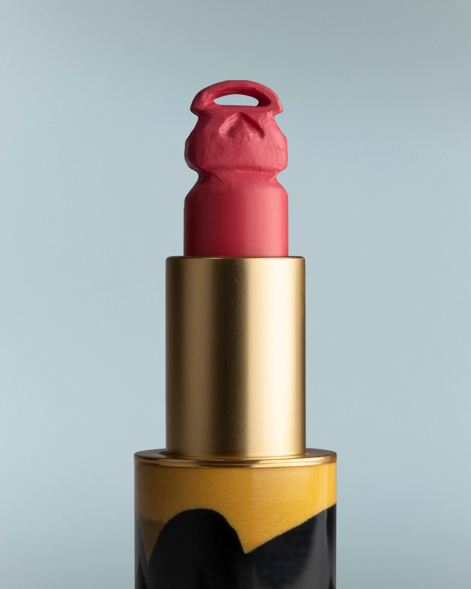 Lipstick with gold casing on a gray background