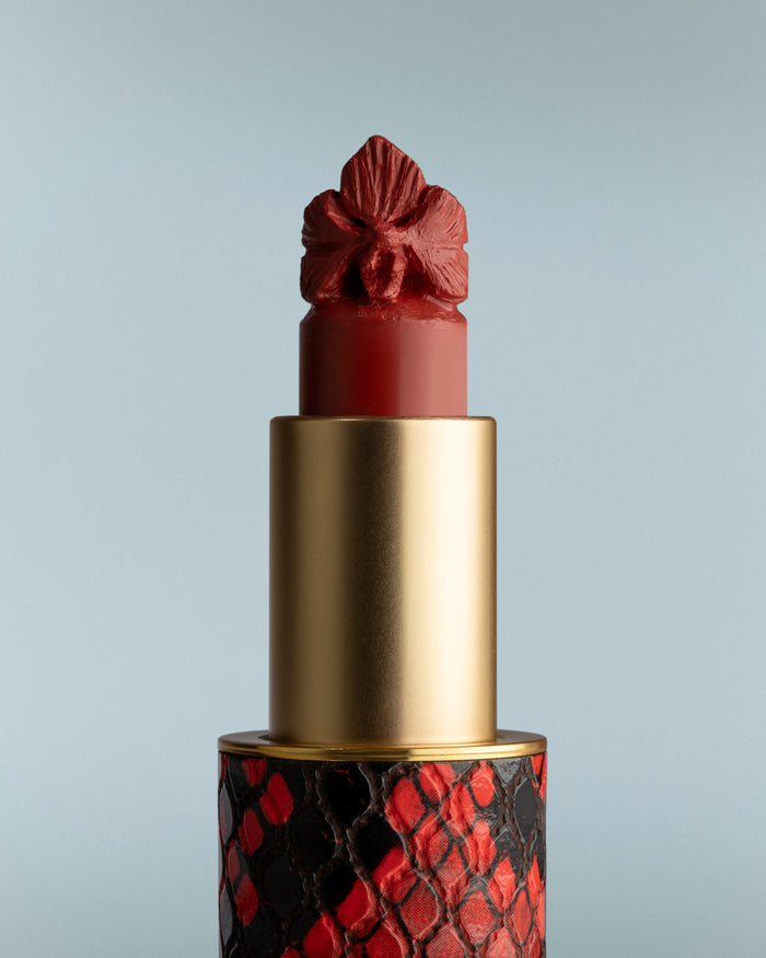 Lipstick with a decorative red and gold cap on a gray background