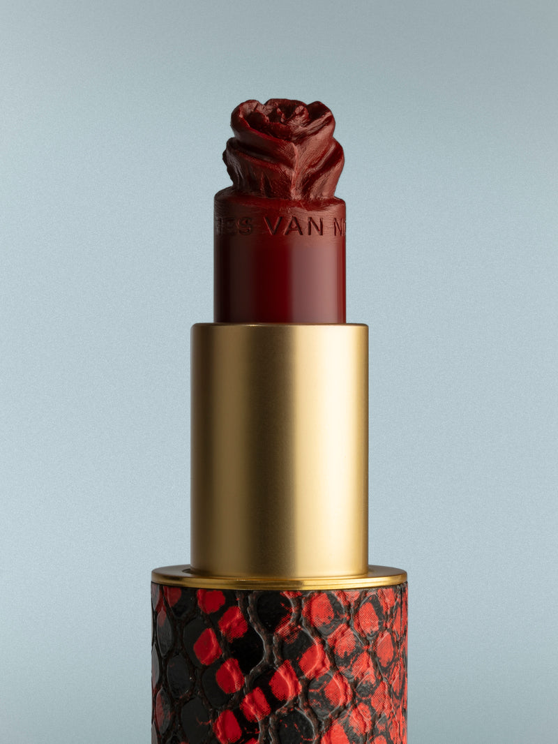 Lipstick with a decorative red and black pattern on a gray background