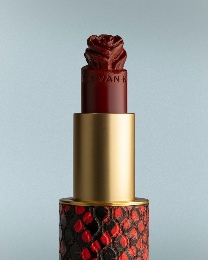 Lipstick with a decorative red and black pattern on a gray background