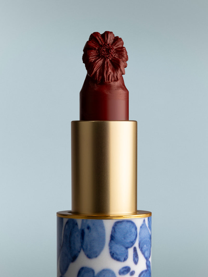 Lipstick with a decorative cap and blue patterned case on a gray background