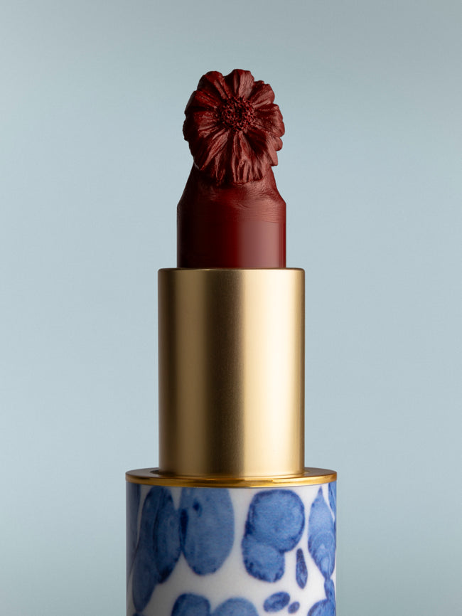 Lipstick with a decorative cap and blue patterned case on a gray background