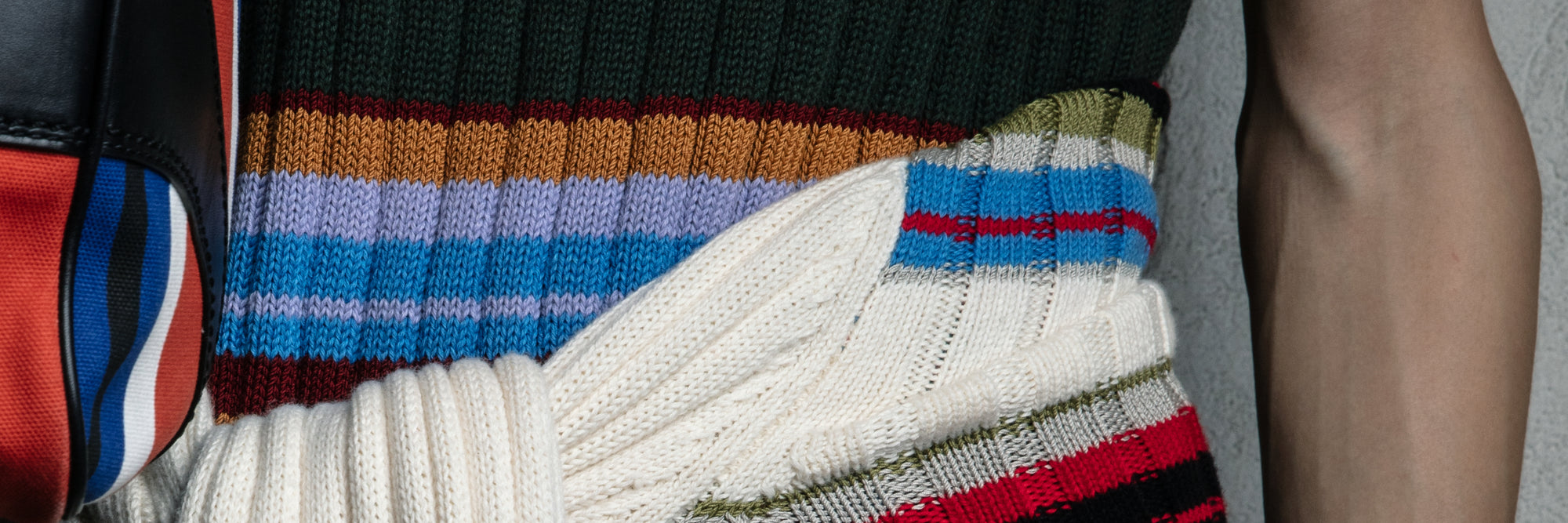 Close-up of a colorful striped sweater with a white garment underneath - Dries Van Noten.
