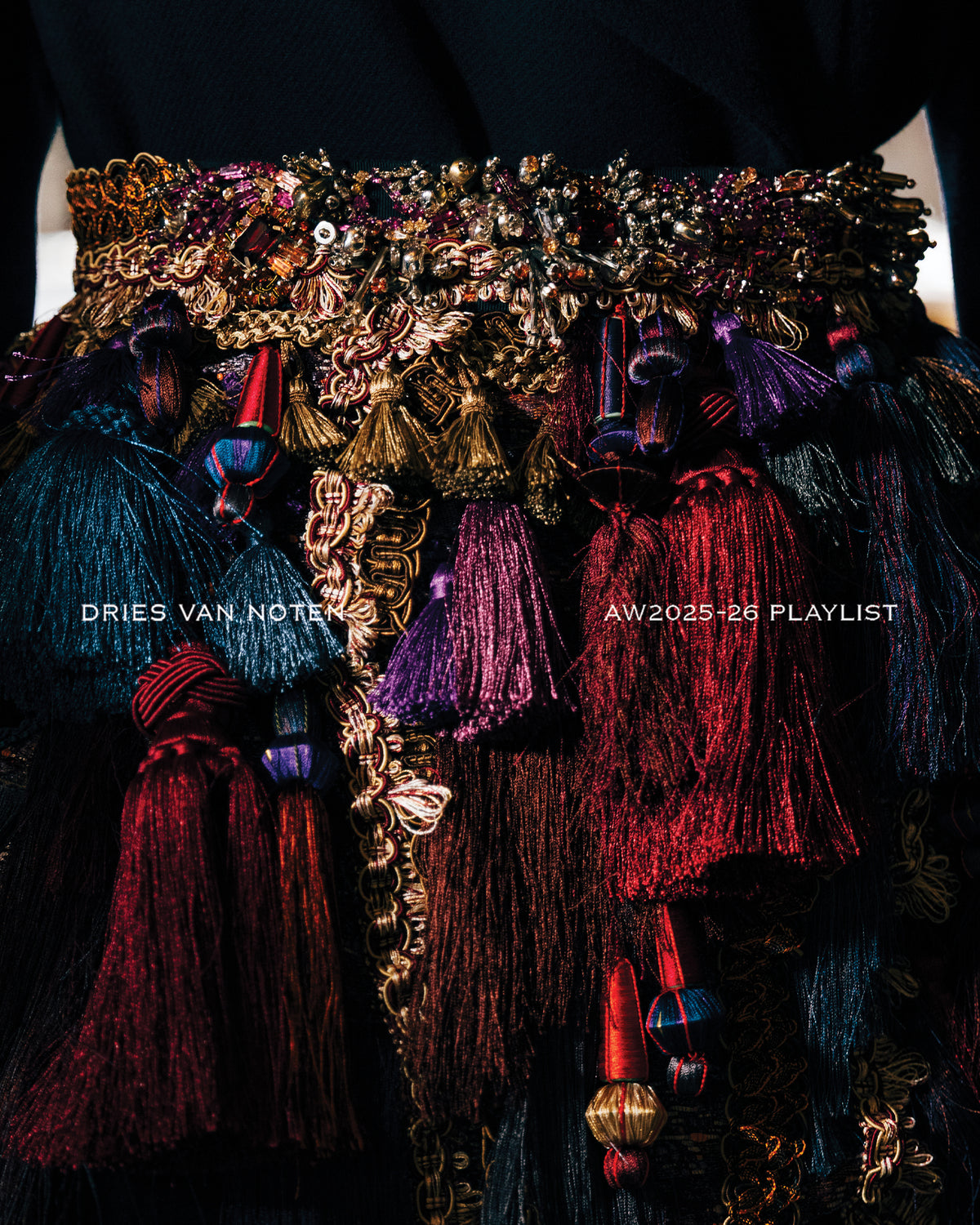 Colorful, ornate belt with tassels and sequins on a dark background, featuring Dries Van Noten branding.