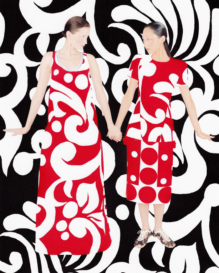Two models holding hands, wearing red dresses with bold white patterns, set against a black and white graphic background 