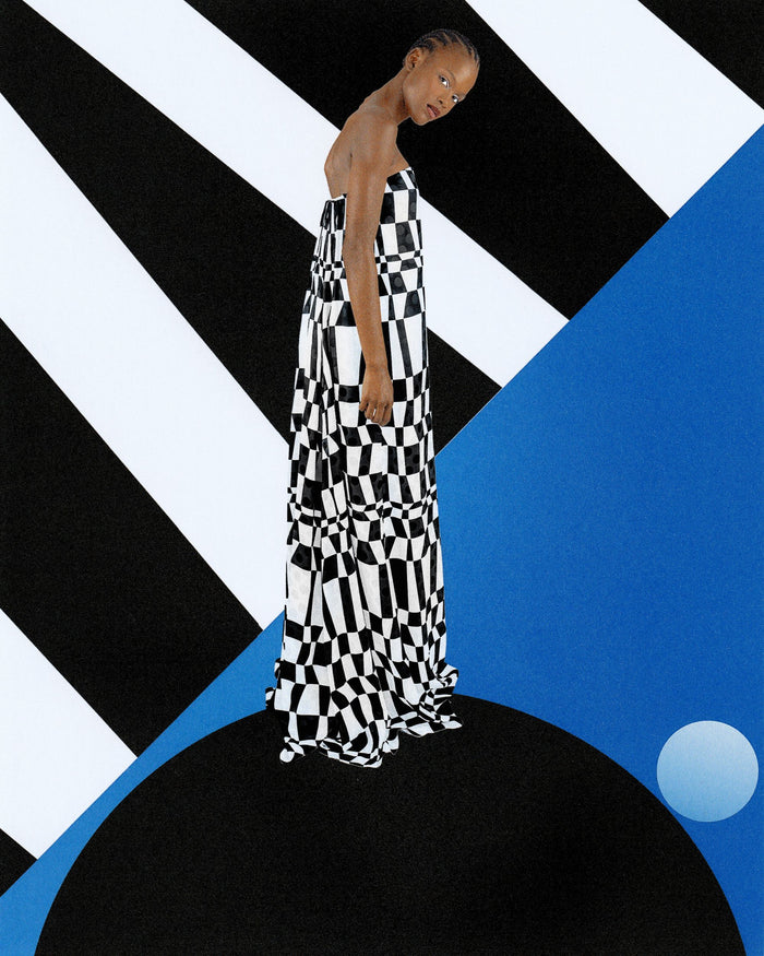 Model wearing a black and white patterned dress agains a graphic background with bold shapes