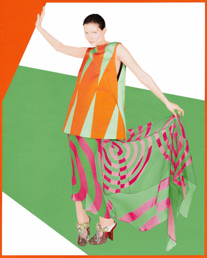 Model wearing a colorful outfit with geometric patterns, posing against a bold graphic background 