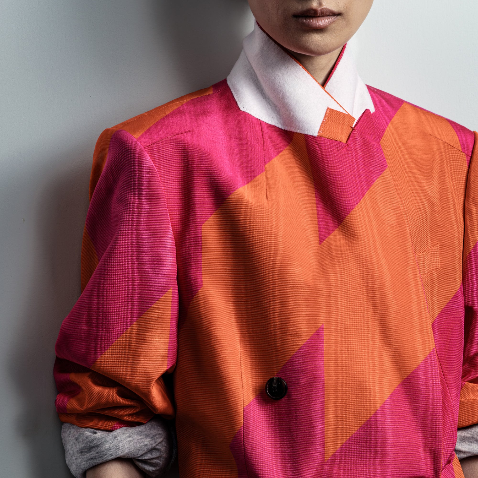 Person wearing a vibrant, geometric-patterned shirt with pink and orange colors against a neutral background - Dries Van Noten