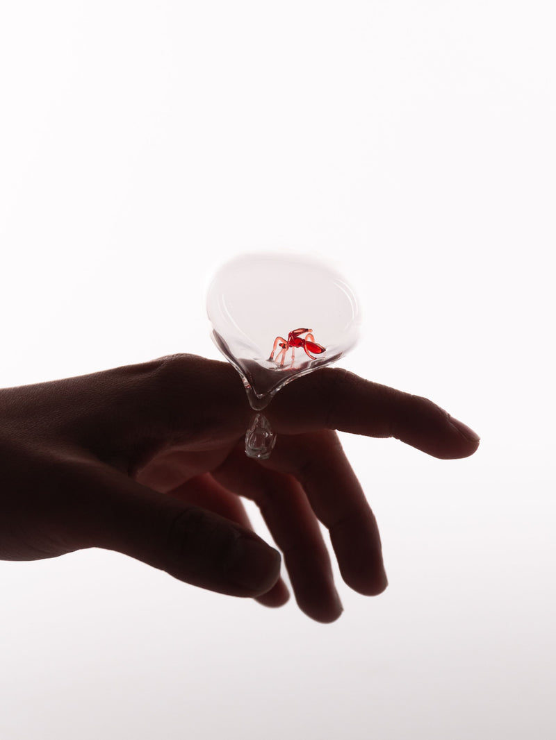 Hand holding a glass object with a small red detail inside