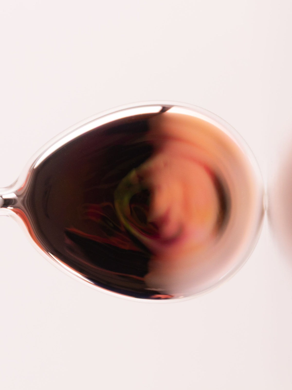 Hand holding a glass object with amber reflections against a white background