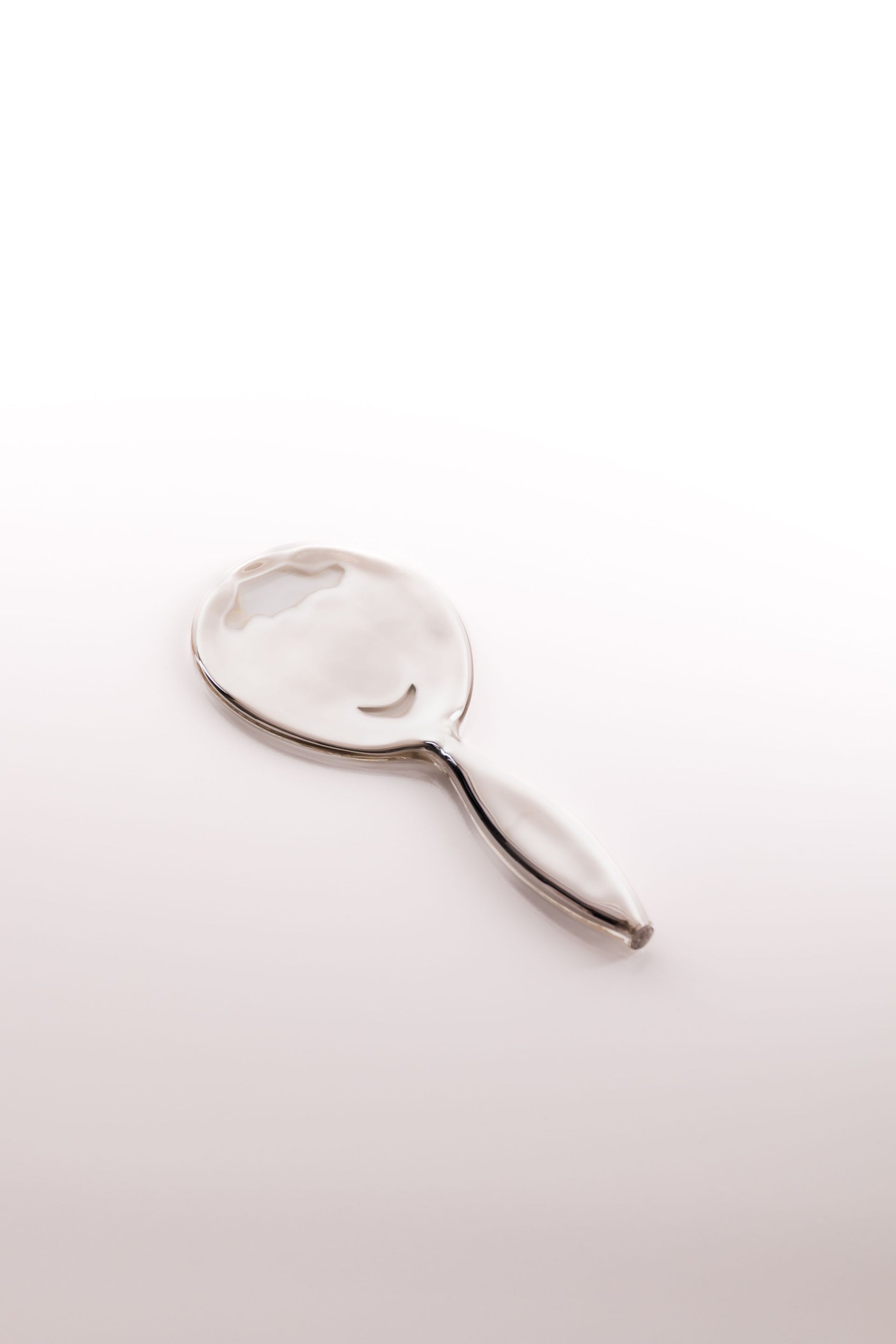 Clear glass object with an oval shape and a handle