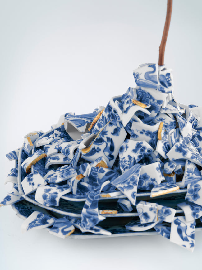 Stack of blue and white ceramic plates with floral patterns on a white background - Dries Van Noten