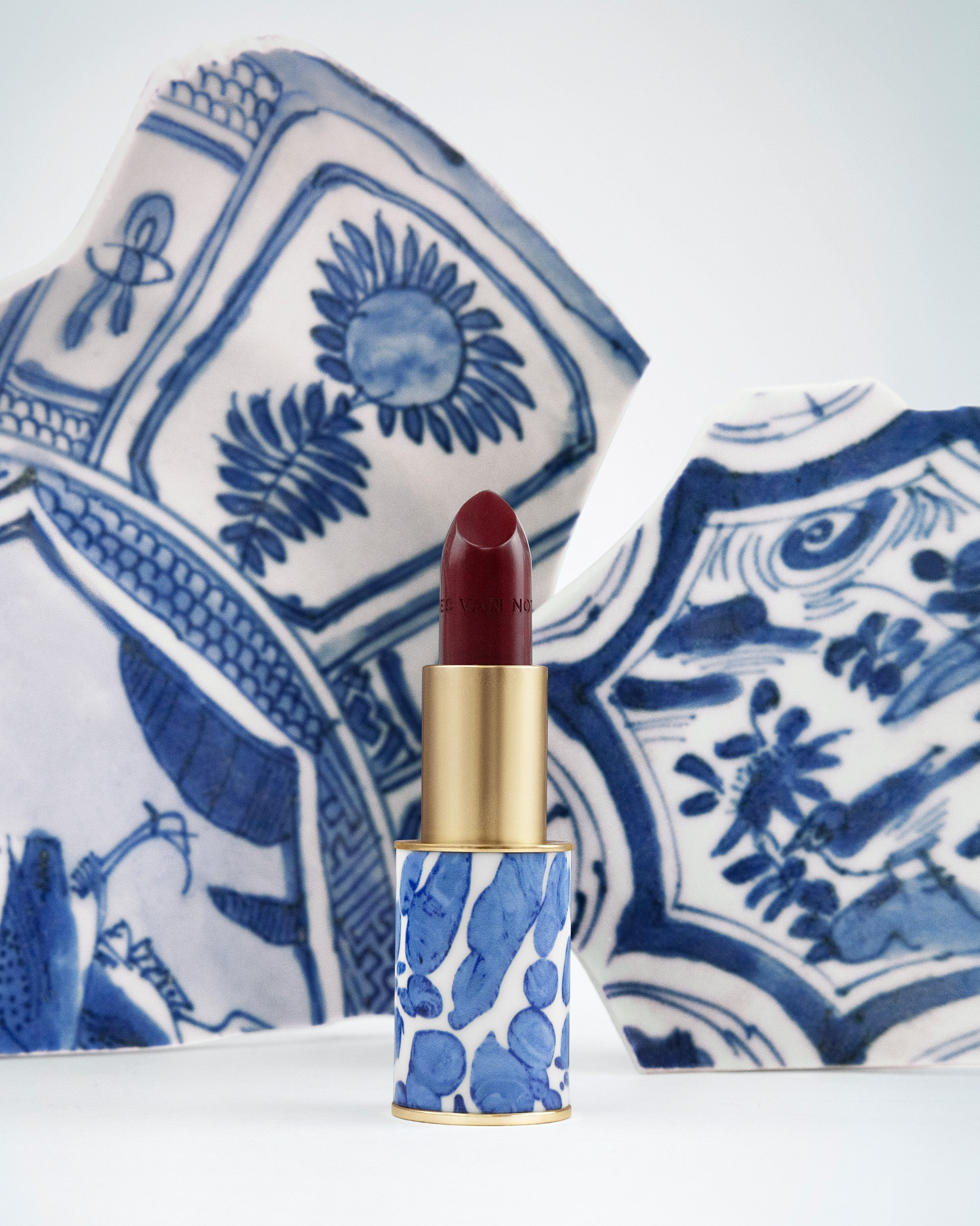 Lipstick with blue and white patterned case on a decorative plate - Dries Van Noten