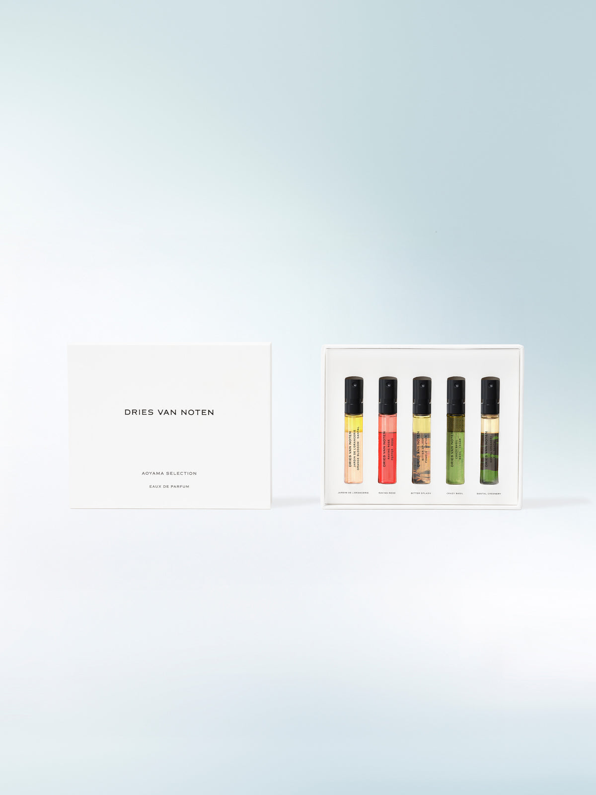 Set of six small bottles with colorful caps on a light blue background, featuring the brand 'Dries Van Noten'.