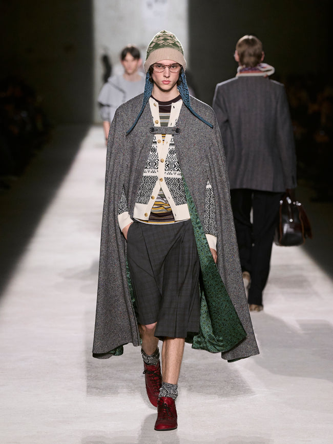 Model walking on a runway wearing a long coat and patterned hat - Dries Van Noten