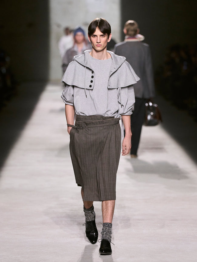 Model walking on a runway wearing a gray outfit with a ruffled top and pleated skirt - Dries Van Noten