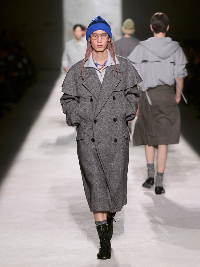 Model wearing a gray coat and blue beanie on a runway - Dries Van Noten