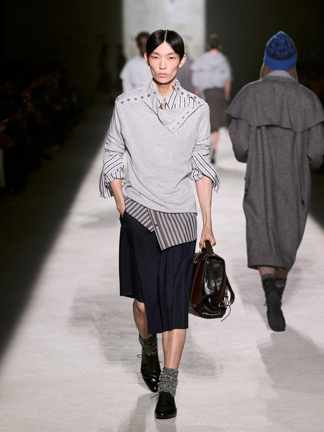 Model walking on a runway wearing a stylish outfit with a gray sweater and black skirt - Dries Van Noten