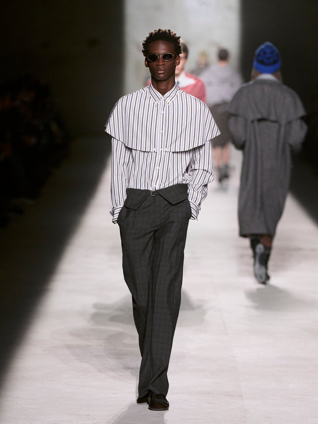 Model walking on a runway wearing a striped shirt and dark pants - Dries Van Noten