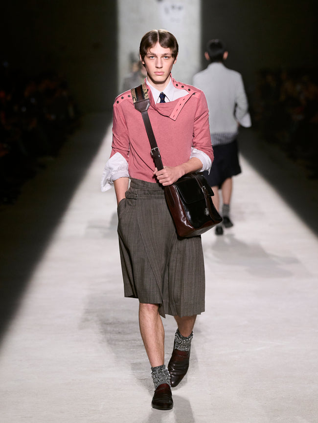Model walking on a runway wearing a pink top and gray skirt with a brown bag - Dries Van Noten