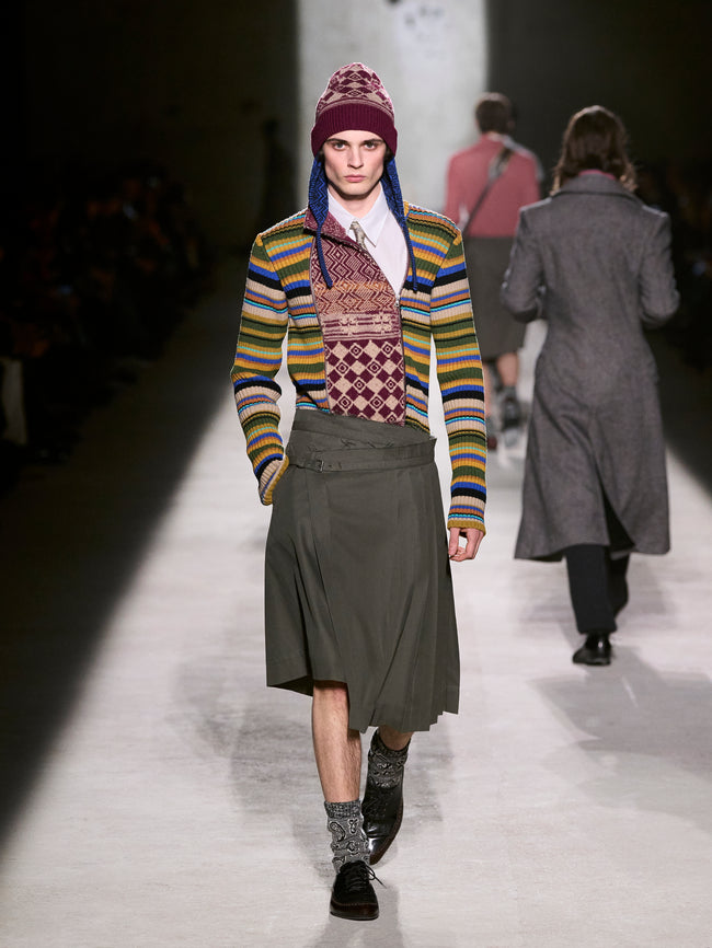 Model walking on a runway wearing a colorful knit sweater and patterned hat - Dries Van Noten