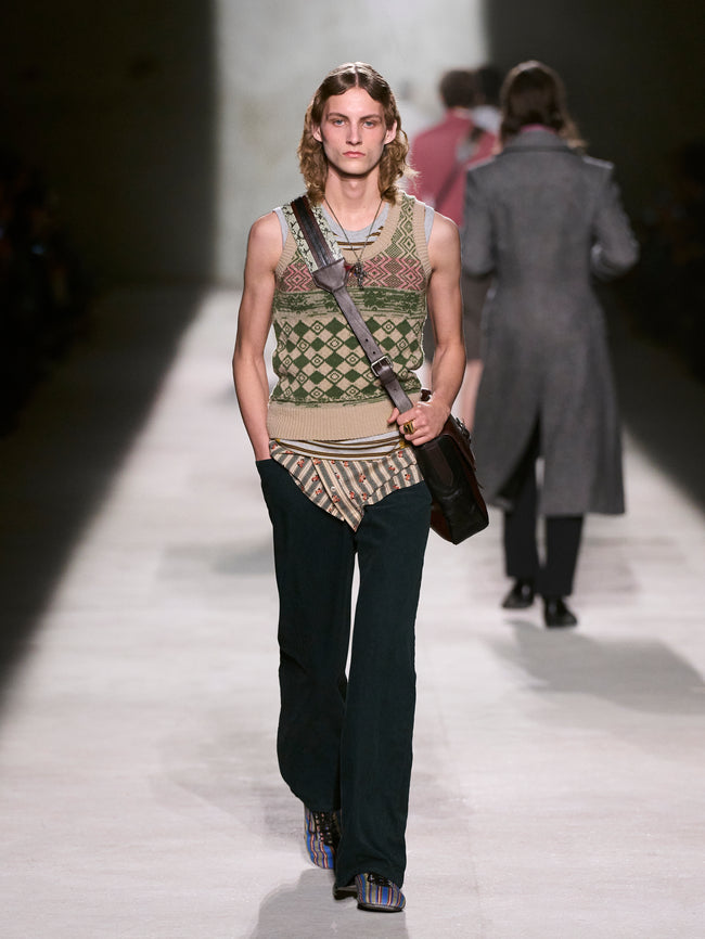 Model walking on a runway wearing a patterned sleeveless top and black pants - Dries Van Noten