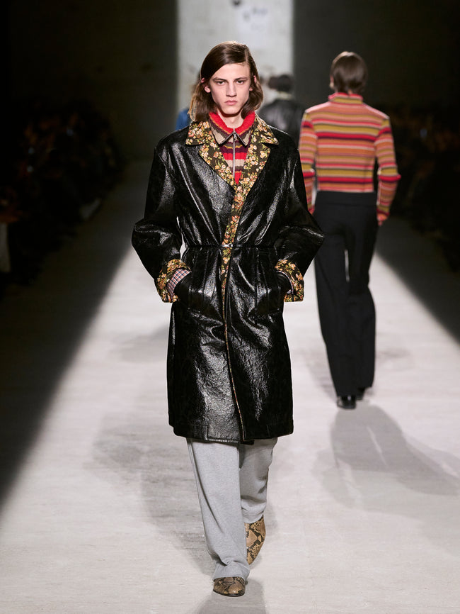 Model walking on a runway wearing a black coat with gold embroidery - Dries Van Noten