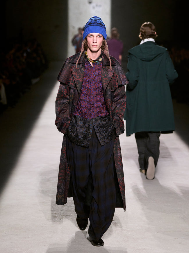 Model walking on a runway wearing a textured coat and blue beanie - Dries Van Noten