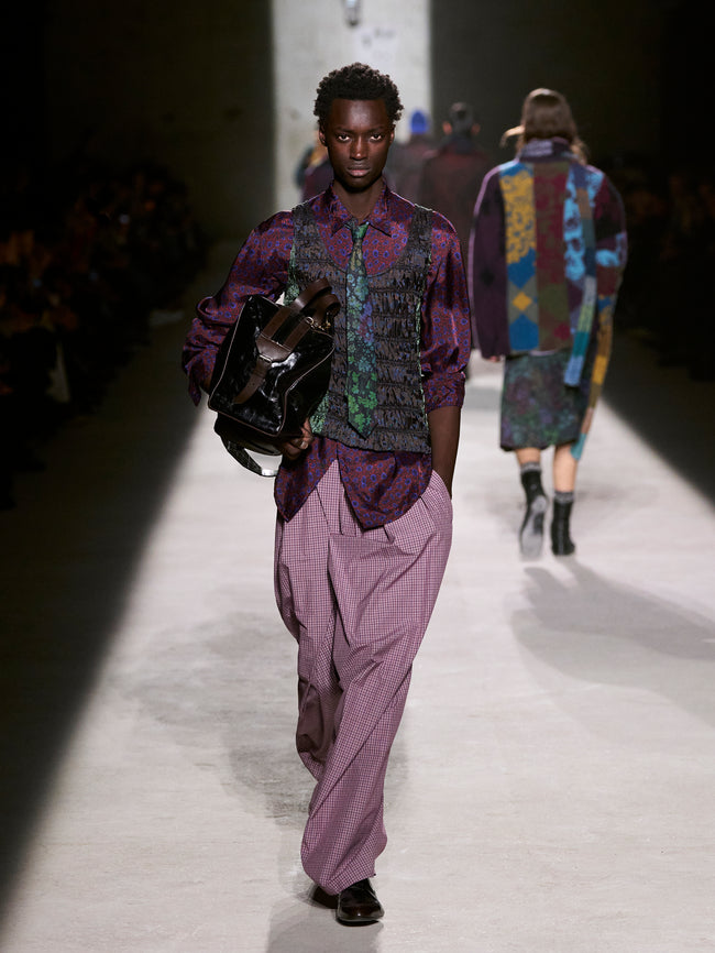 Model walking on a runway wearing a purple outfit with a patterned vest - Dries Van Noten