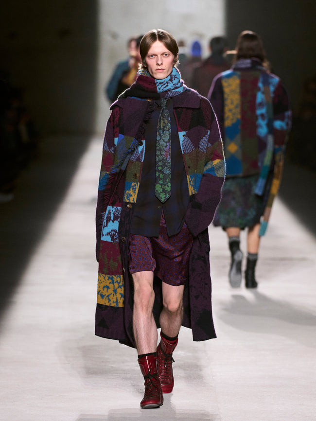Model walking on a runway wearing a colorful, patterned coat and scarf - Dries Van Noten