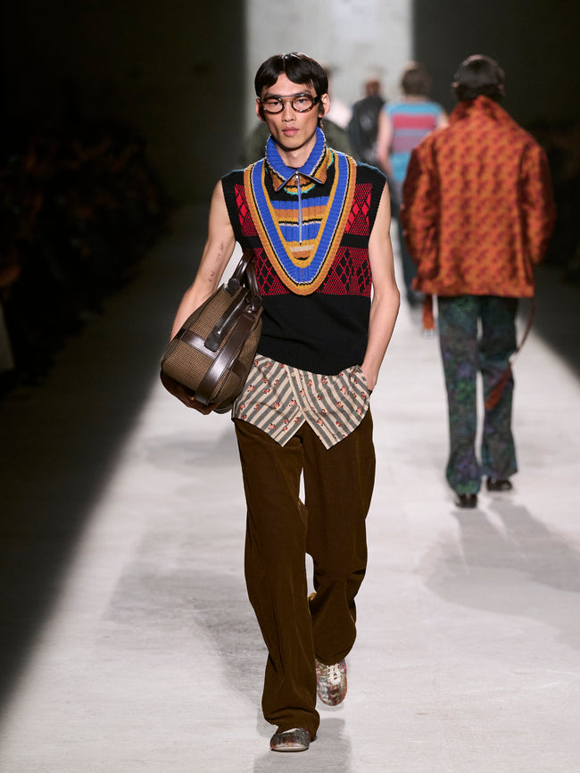 Model walking on a runway wearing a colorful sleeveless top and patterned pants - Dries Van Noten
