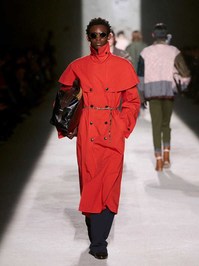 Model wearing a red coat on a fashion runway - Dries Van Noten