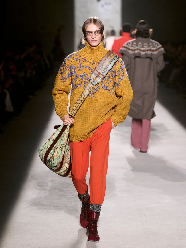 Model walking on a runway wearing a mustard yellow sweater and red pants - Dries Van Noten