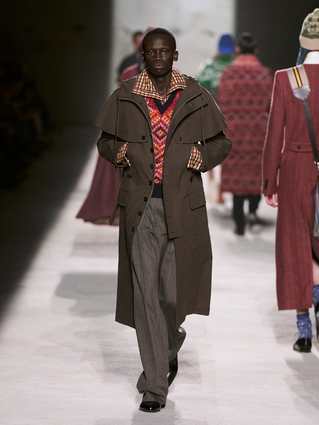 Man walking on a runway wearing a long brown coat and patterned shirt - Dries Van Noten