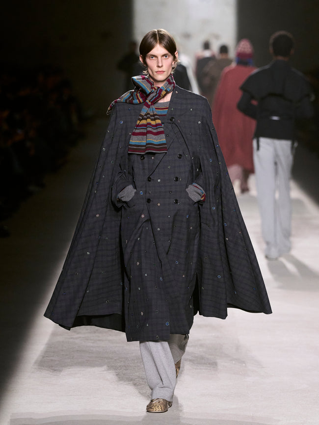 Model wearing a long dark coat with a colorful scarf on a runway - Dries Van Noten