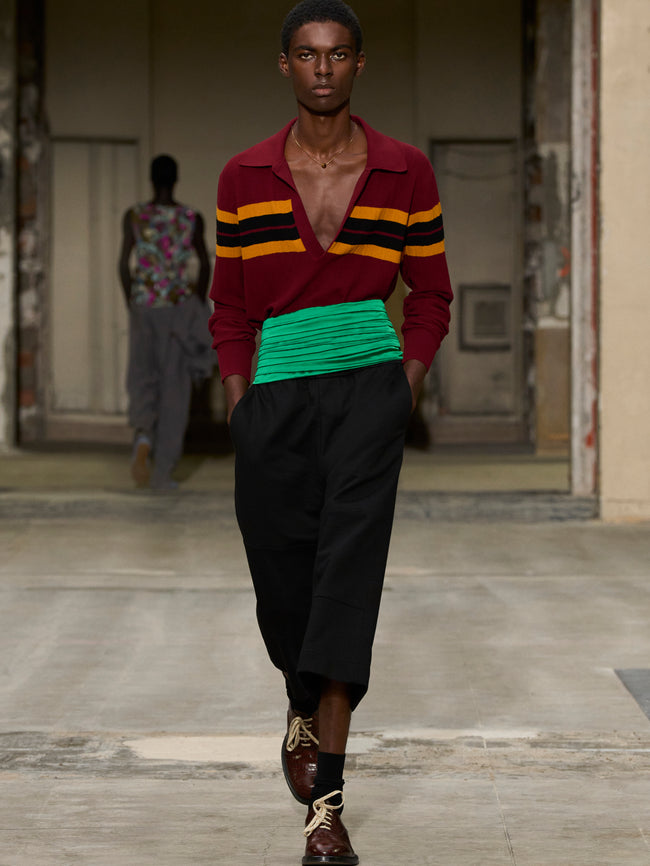 Model walking on a runway wearing a colorful sweater and black pants. - Dries Van Noten