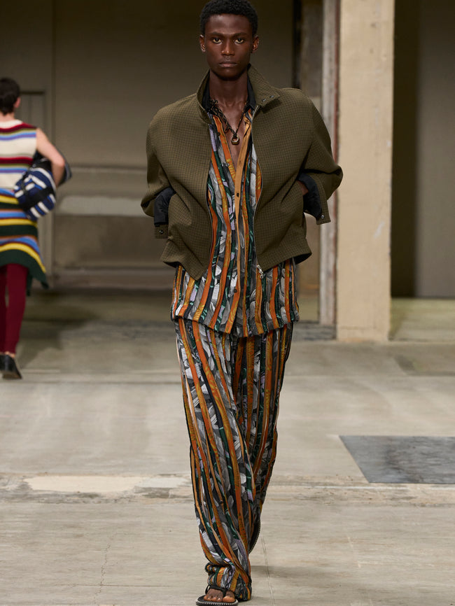 Model walking on a runway wearing a patterned outfit with a blurred background - Dries Van Noten