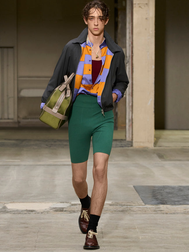 Model walking on a runway wearing a colorful outfit with green shorts. - Dries Van Noten