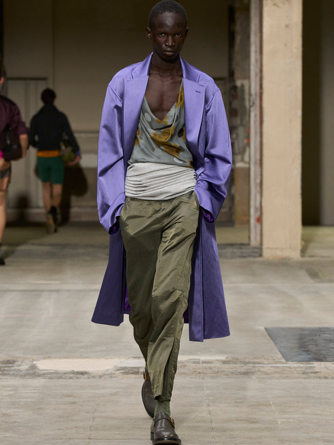 Man walking on a runway wearing a purple coat and green pants. - Dries Van Noten
