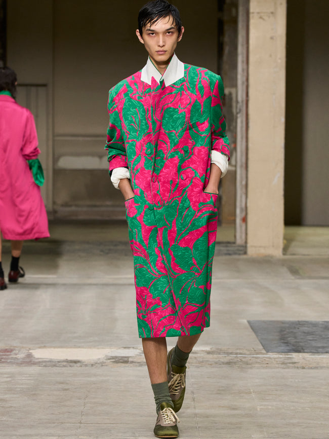 Model wearing a vibrant pink and green patterned outfit on a runway. - Dries Van Noten