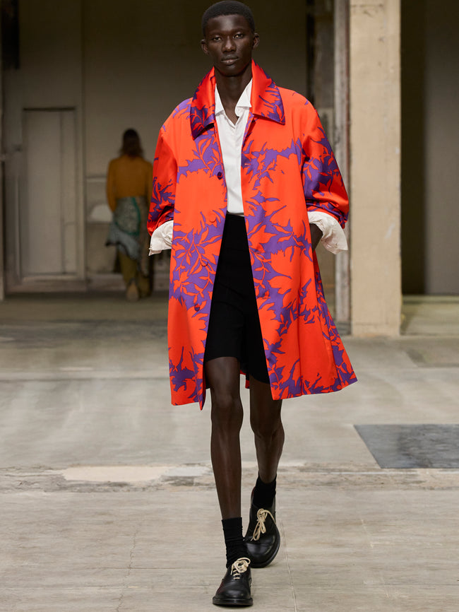 Model wearing a vibrant red and blue coat on a runway - Dries Van Noten