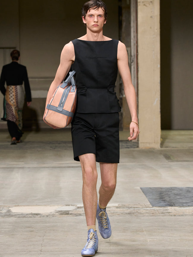 Man walking with a beige bag in an indoor setting - Dries Van Noten