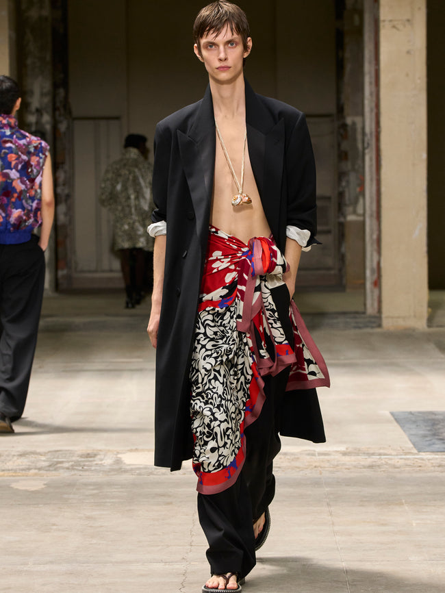 Model wearing a black robe over a colorful patterned skirt on a runway. - Dries Van Noten