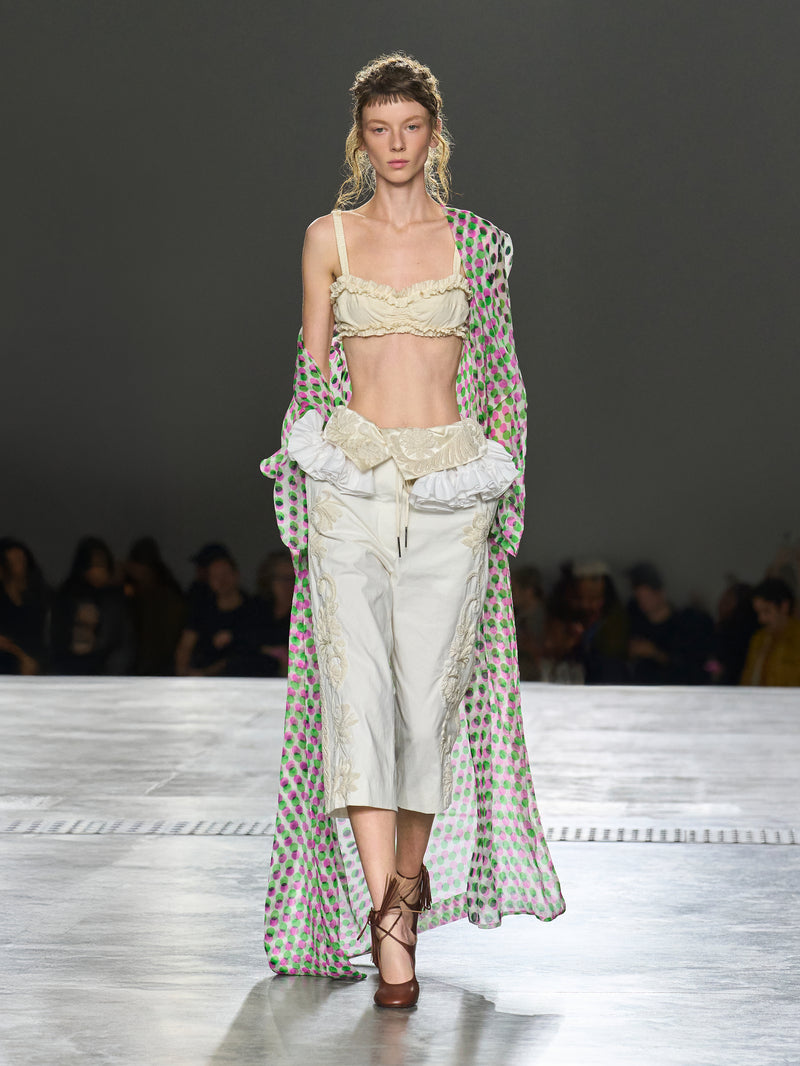 Model walking on a runway wearing a stylish outfit with a patterned cover-up.