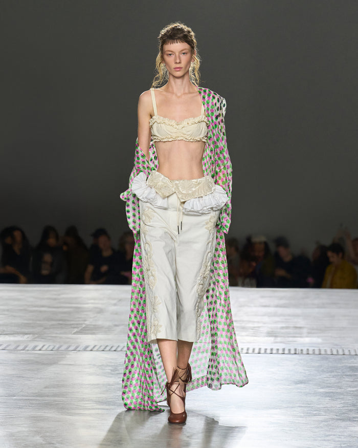 Model walking on a runway wearing a stylish outfit with a patterned cover-up.