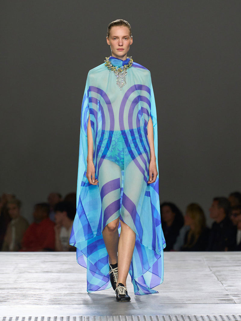 Model wearing a colorful dress with a geometric pattern on a runway.