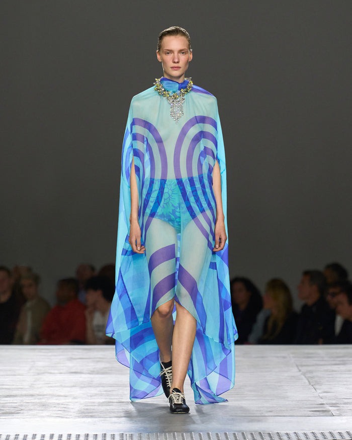 Model wearing a colorful dress with a geometric pattern on a runway.